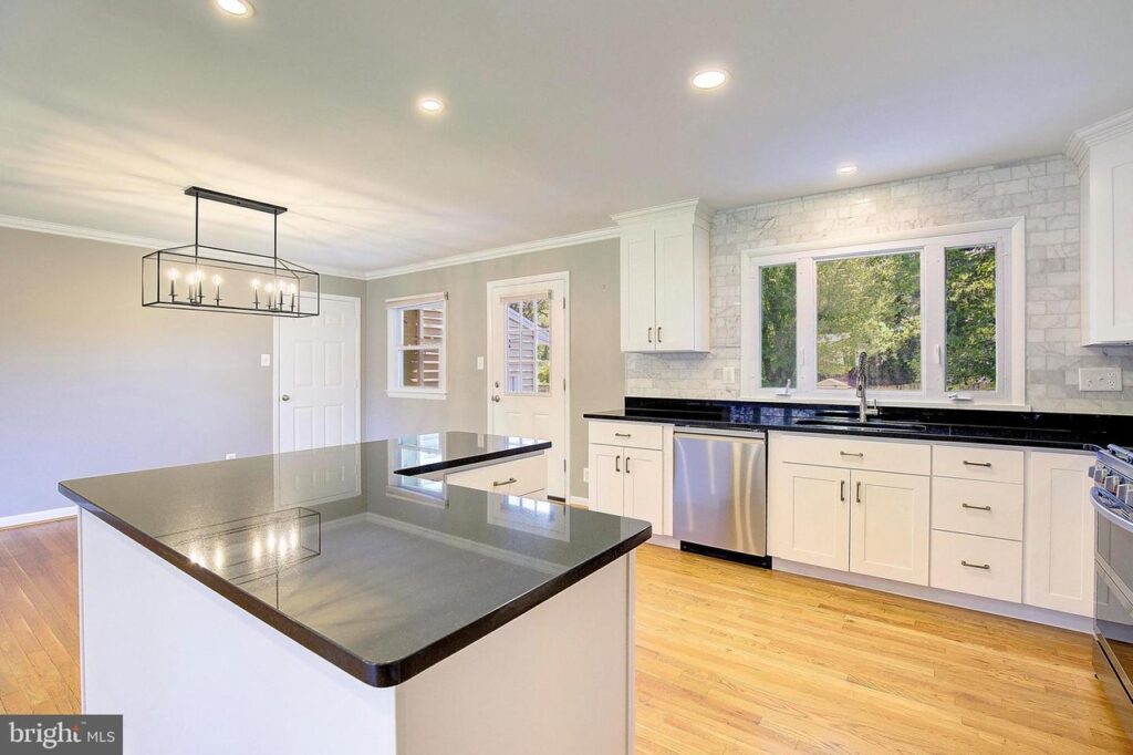 First time home buyer's white kitchen cabinets, black countertops, tile backsplash and wood floors.