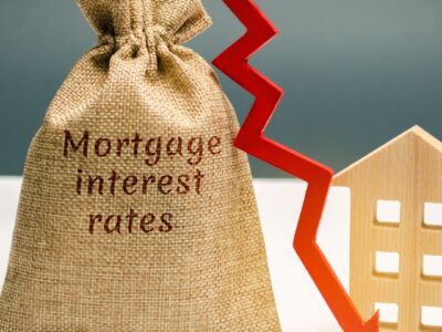 Bag labeled mortgage interest rates with dropping red arrow showing spring real estate market